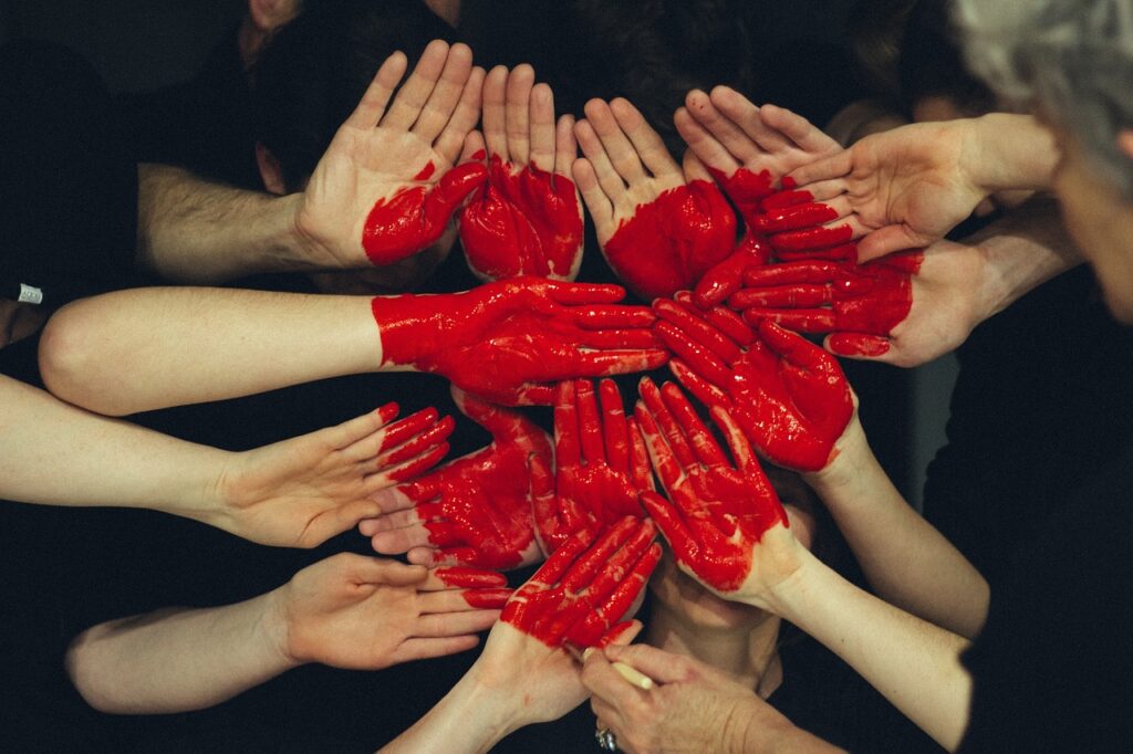 Collective depiction of love. Hands showing red heart painted