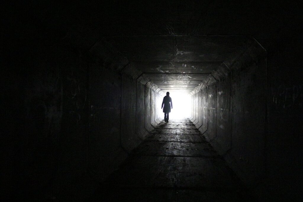 Woman walking to the light at the end of the tunnel